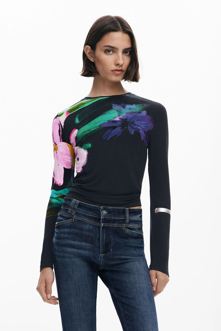 T-shirt floral à manches longues sur fond noir, porté avec jeans, offrant un look élégant et structuré.