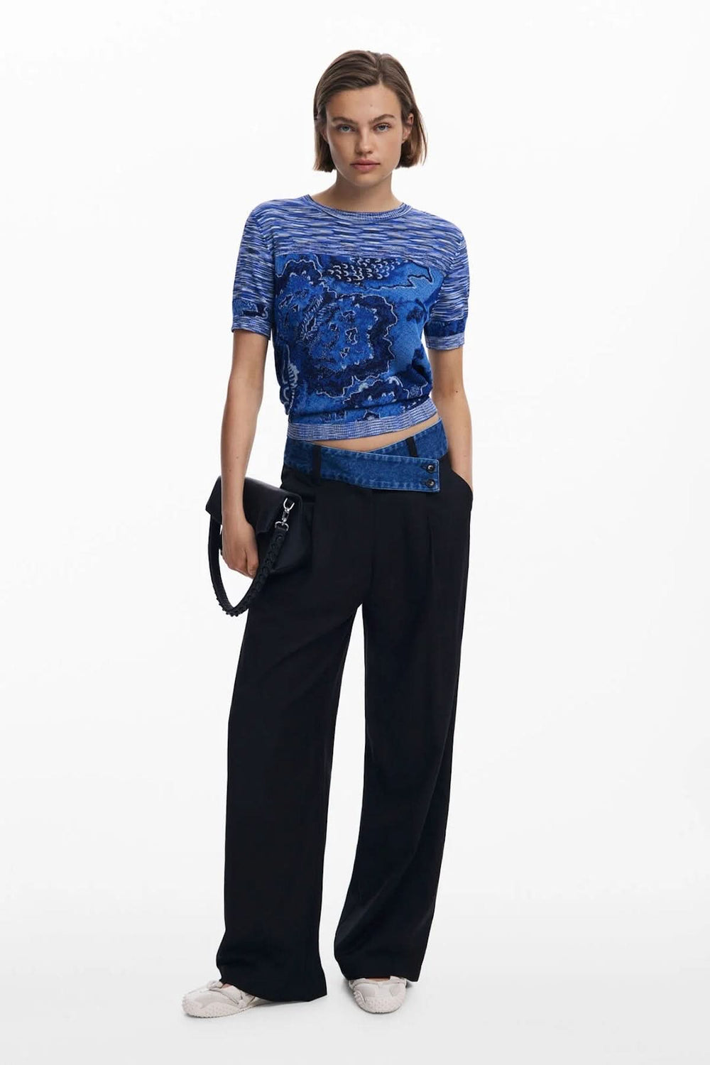 T-shirt en tricot à manches courtes, motif texturé bleu, coupe ajustée, porté avec un pantalon noir large.