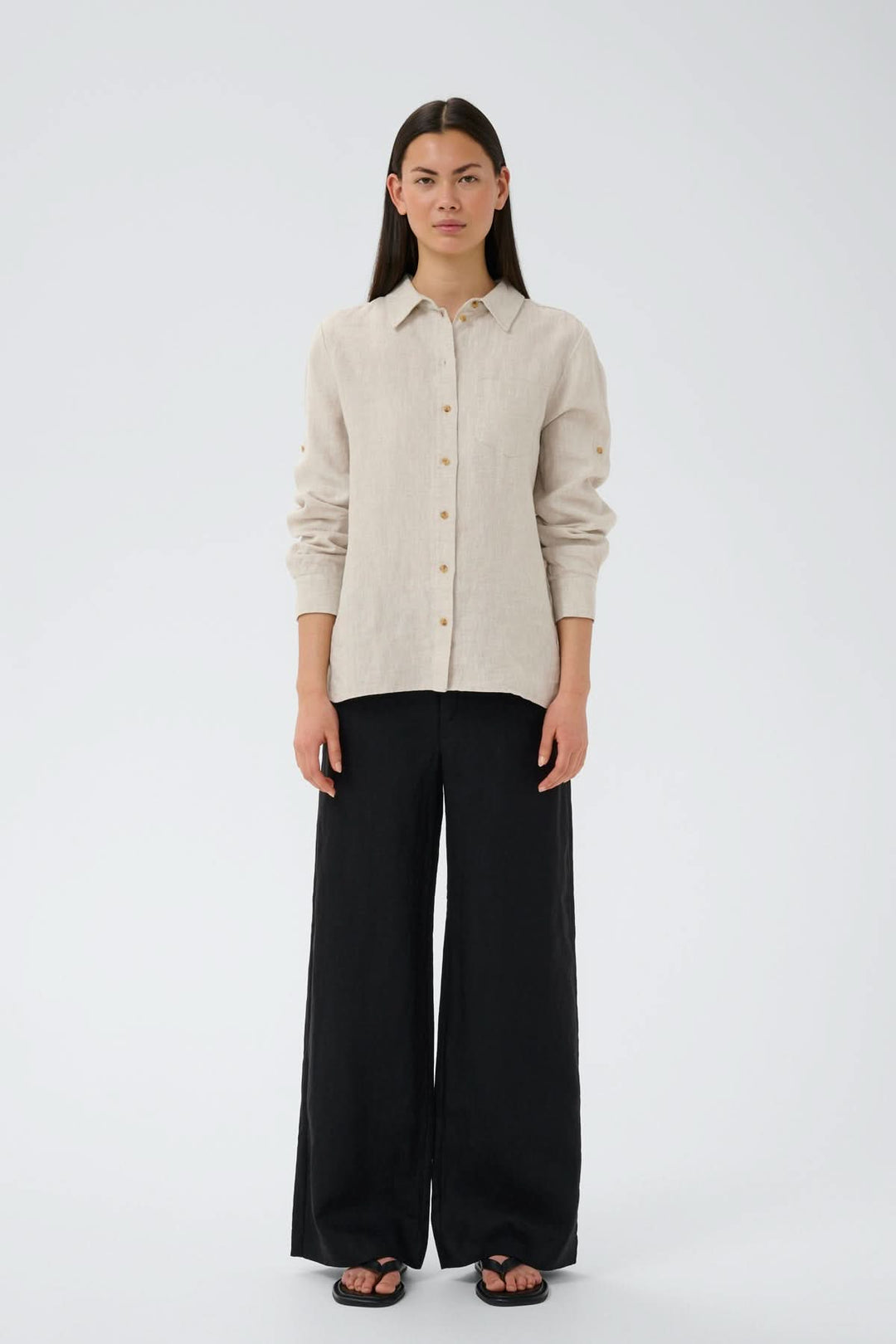 Modèle portant le Pantalon de lin Solina avec taille haute et jambes larges, style décontracté avec chemise beige.