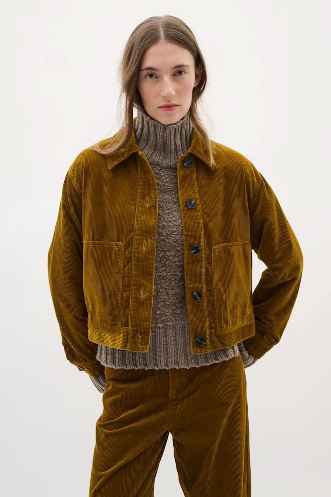 Veste en velours côtelé brune avec col chemise, portée sur un pull gris, pour un look rétro tendance.