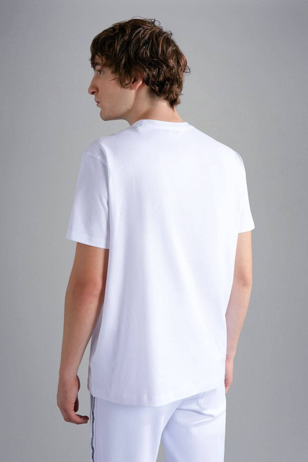 Homme portant un T-shirt blanc vu de dos, style décontracté, confort et élégance, avec pantalon assorti.