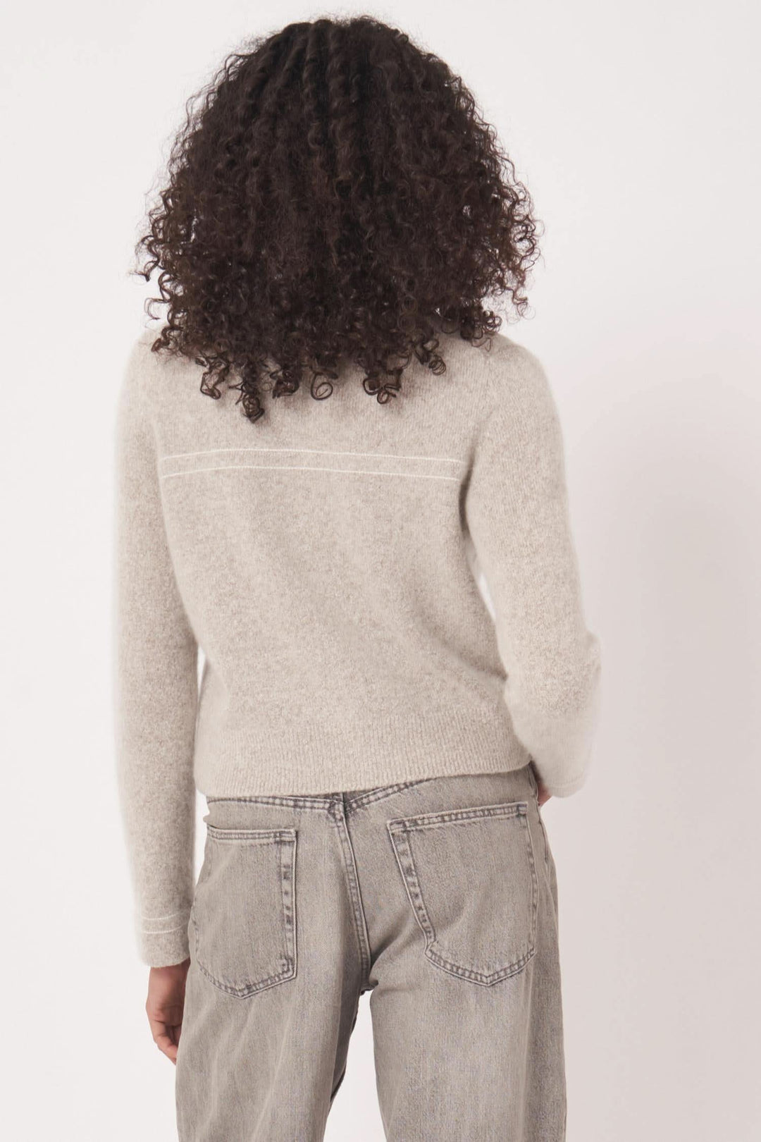 Cardigan en maille beige avec poches plaquées vu de dos, porté avec jeans pour une allure élégante et décontractée.