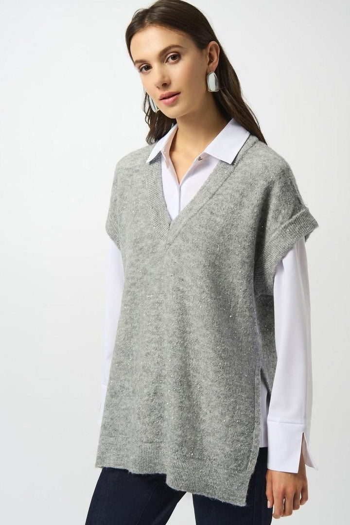 Débardeur en tricot gris avec encolure en V, porté sur une chemise blanche, alliant confort et style.
