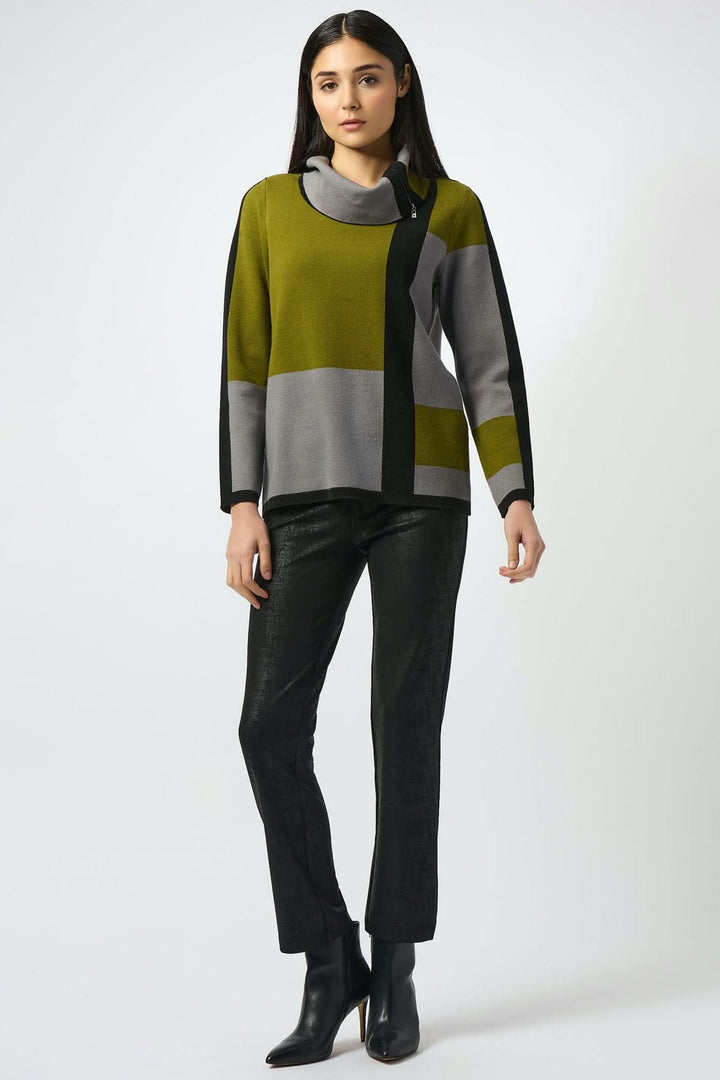 Femme portant un pantalon noir texturé et un pull en couleur vert et gris, style moderne et sophistiqué.