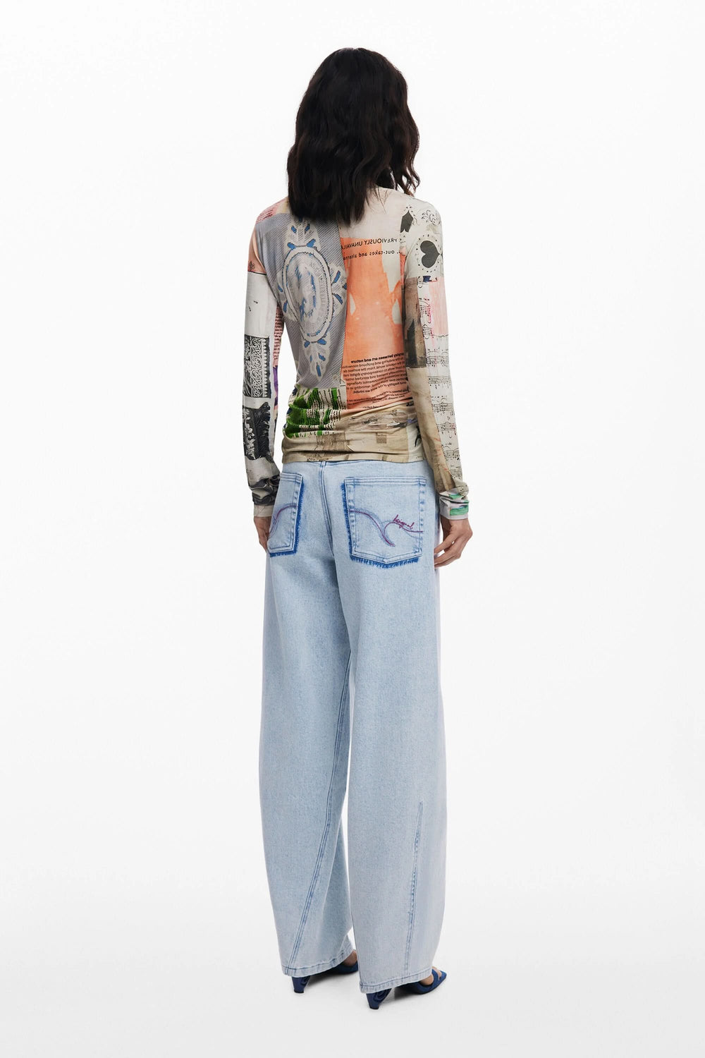 Femme portant un t-shirt à manches longues patchwork avec impression artistique et jeans larges en arrière-plan.