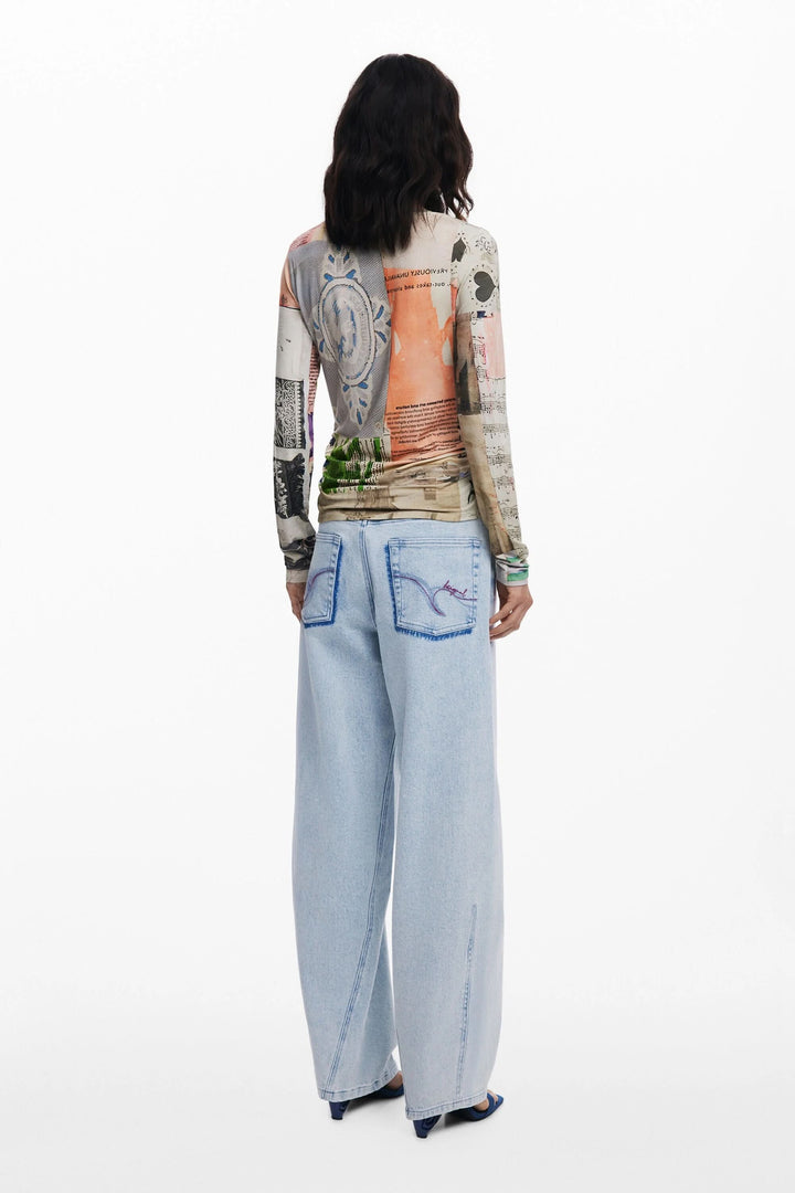 Femme portant un t-shirt à manches longues patchwork avec impression artistique et jeans larges en arrière-plan.