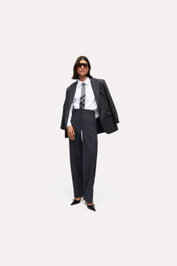 Modèle portant un pantalon Glam Slouch avec une coupe fluide et élégante, parfait pour un look professionnel ou décontracté.