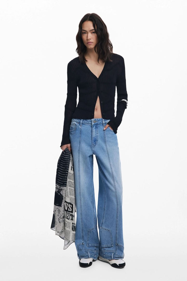 Modèle féminin en pull noir et jeans larges, portant un foulard collage journal en noir et blanc pour un look contemporain.