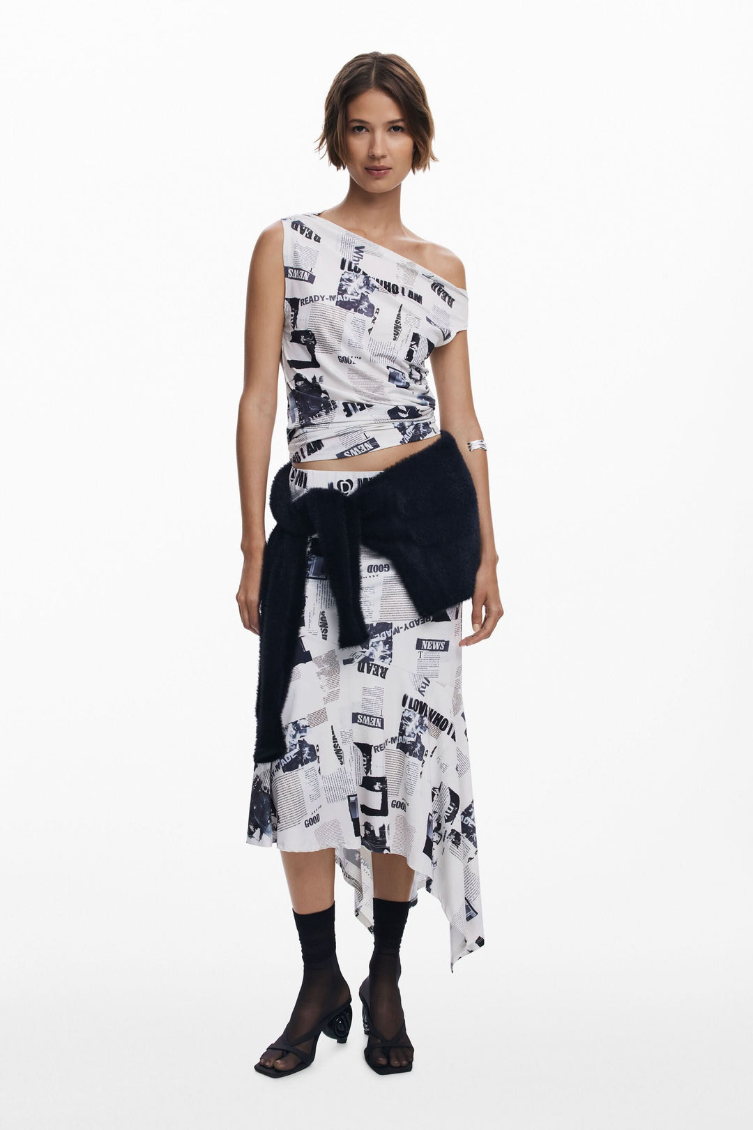 T-shirt drapé asymétrique à col bateau, porté avec une jupe imprimée pour un look moderne et élégant.