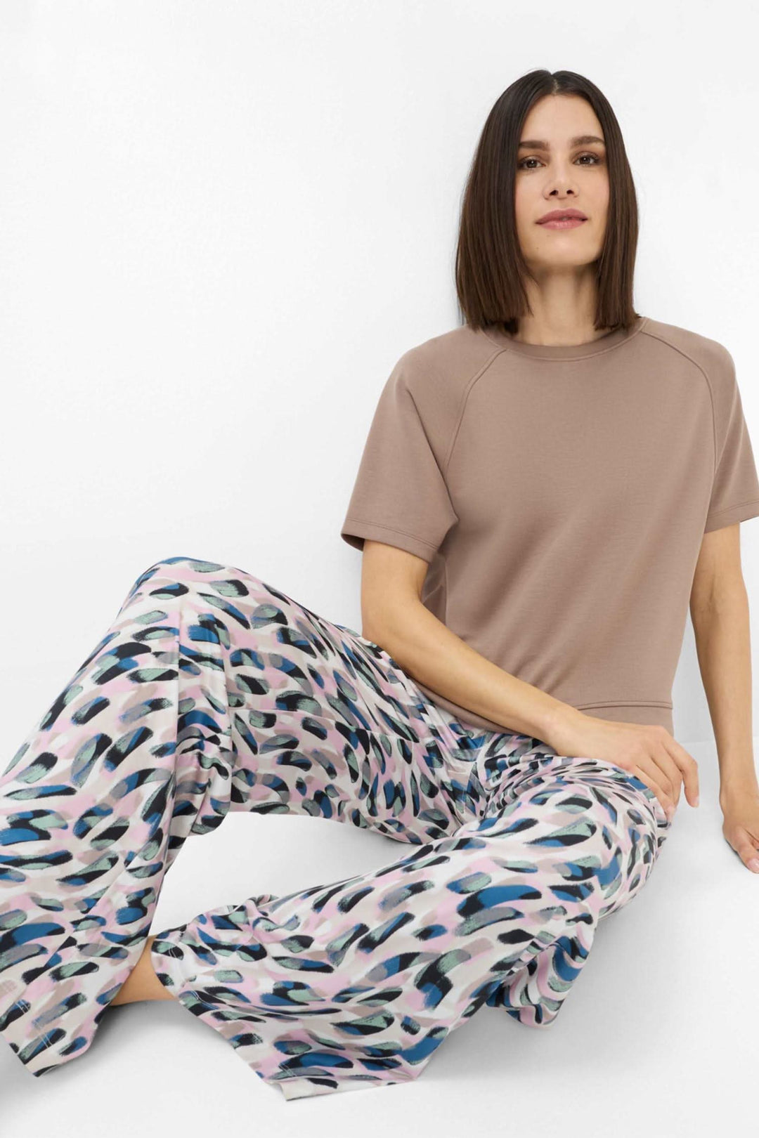 Femme portant un sweatshirt beige oversize avec un pantalon fluide imprimé aux couleurs pastel.