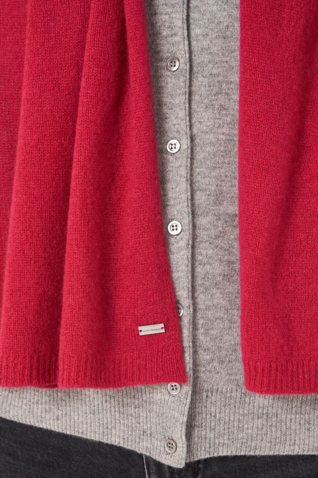 Écharpe droite en cachemire rouge sur un cardigan gris, mettant en valeur la douceur et la qualité de la laine.