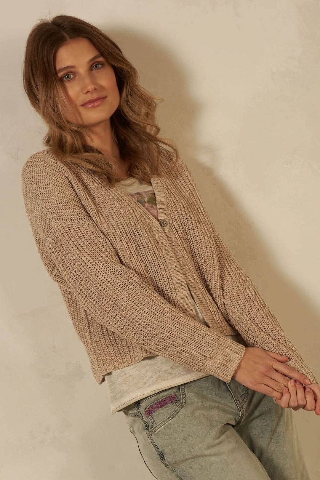 Cardigan en mailles de coton, manches longues, beige, porté par un mannequin avec une coupe décontractée.