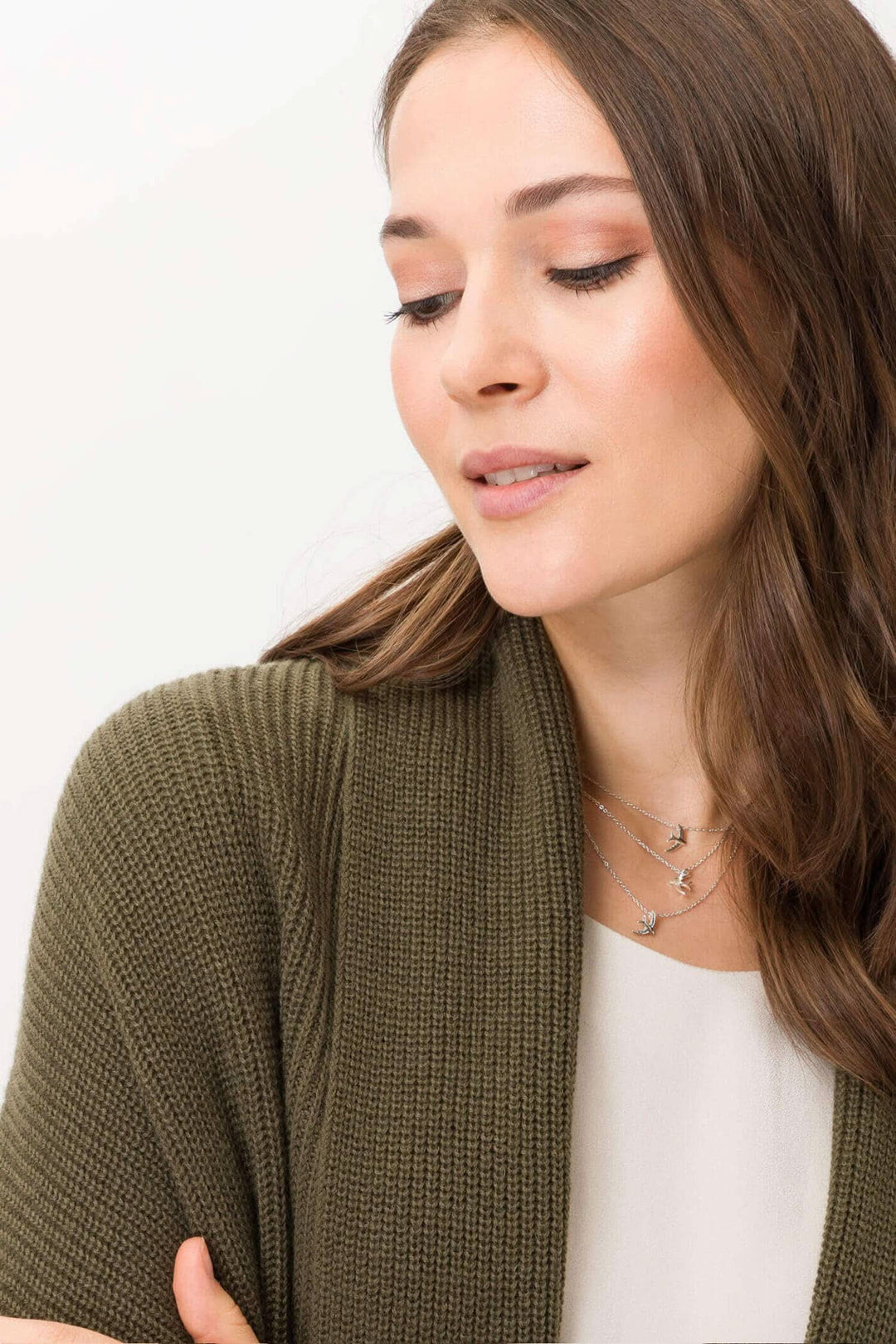 Femme portant un cardigan moderne style Taylor en fine laine mélangée, coloris olive, avec un col châle et bijoux délicats.