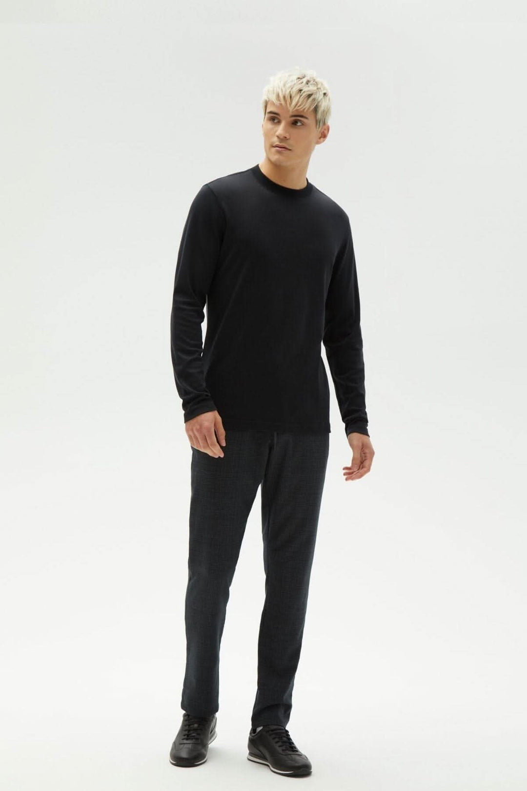 Homme portant un chandail noir à manches longues "Le Barakett" avec un style élégant et confortable.
