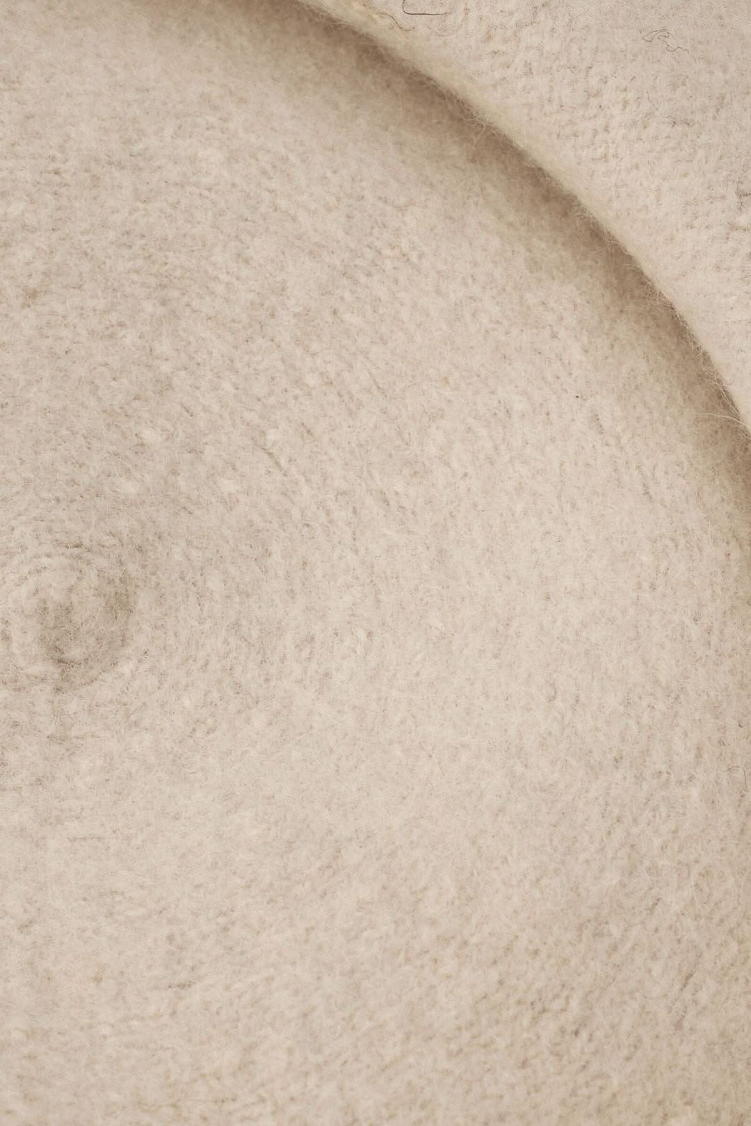 Détails texturés d'un béret en laine doux de couleur beige, mettant en valeur sa finition élégante.