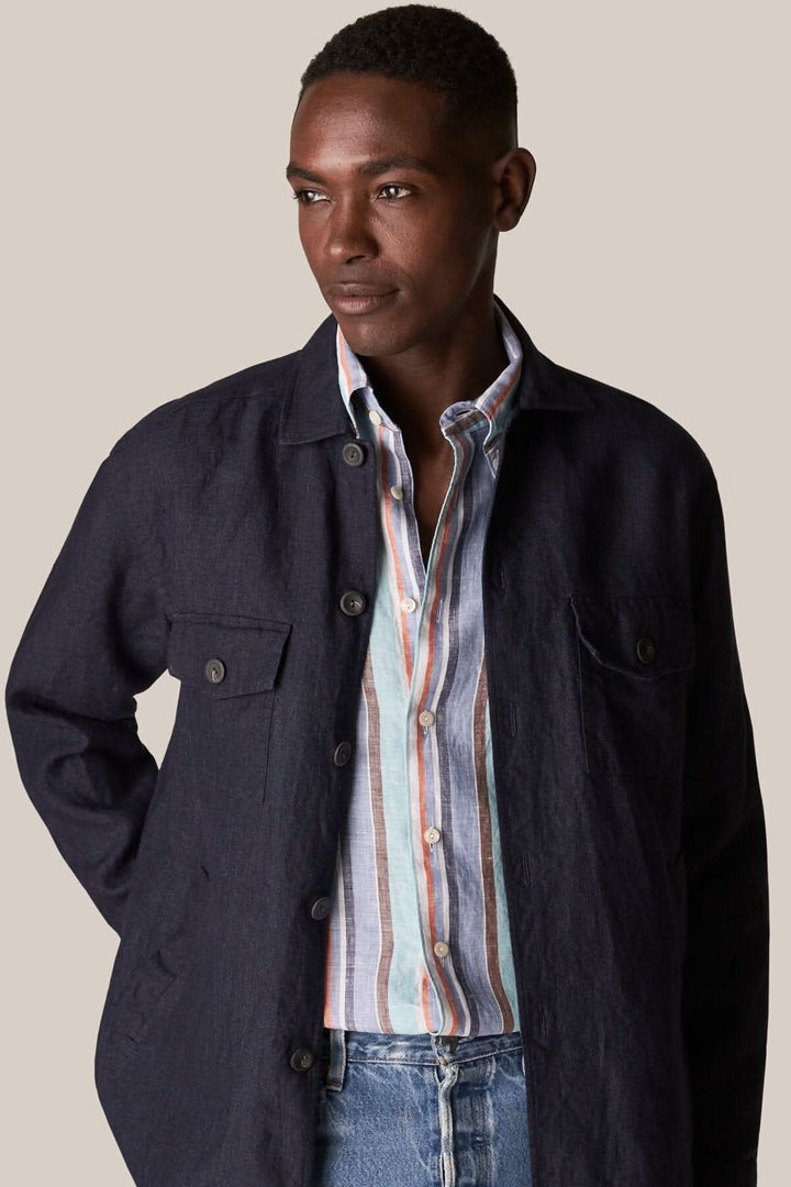 Homme portant une chemise en lin multi-rayures avec une veste noire, style décontracté et moderne.