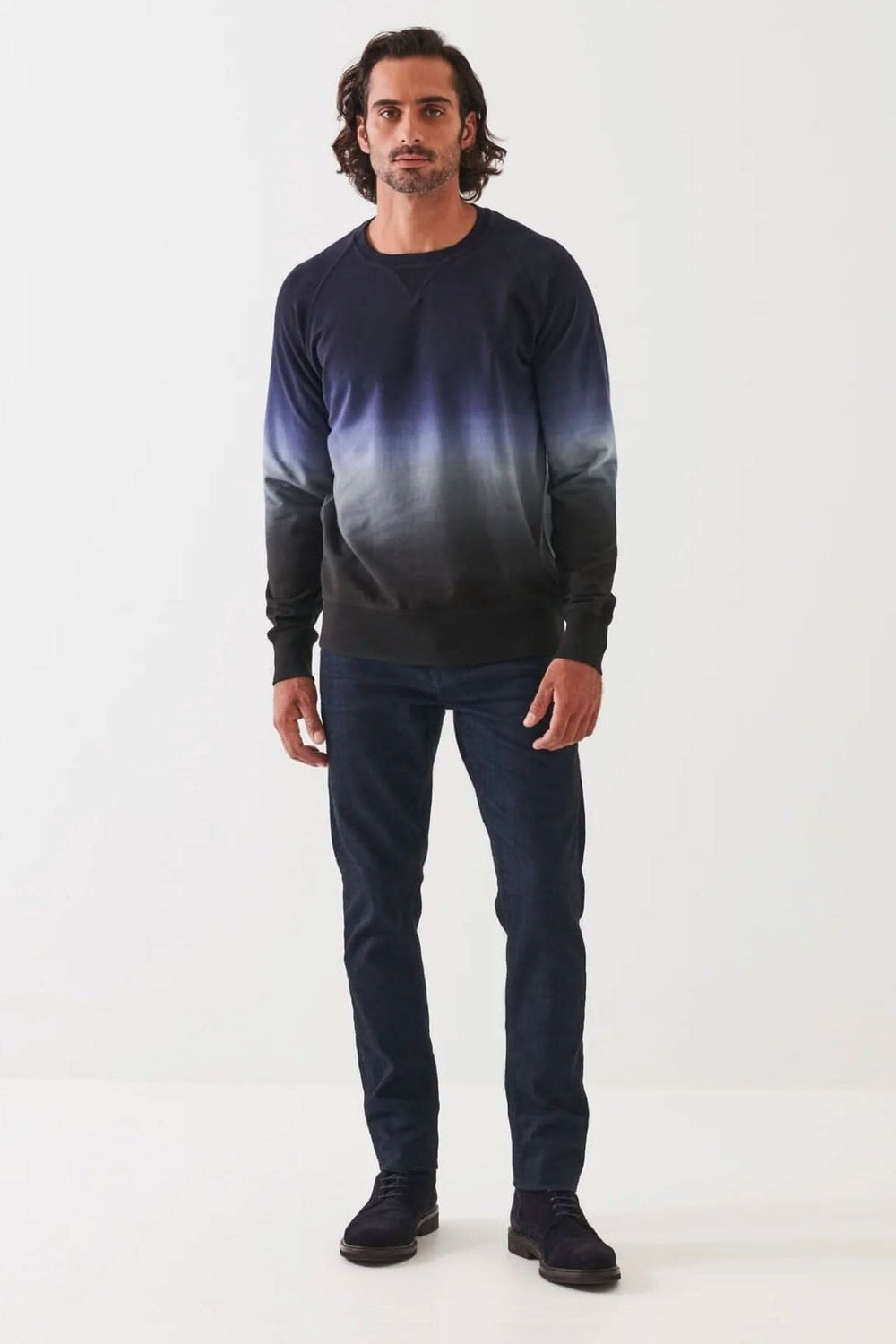 Homme portant un col rond en coton dégradé bleu et noir, associé à un jean, sur fond blanc.