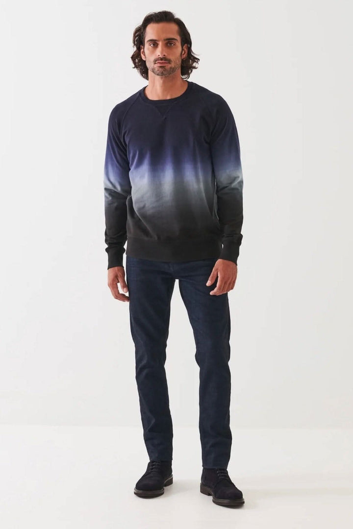Homme portant un col rond en coton dégradé bleu et noir, associé à un jean, sur fond blanc.