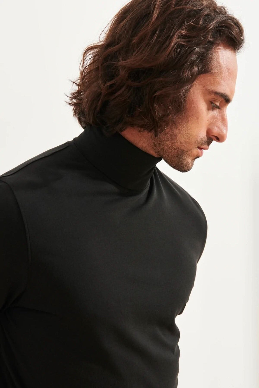 Homme portant un col roulé stretch en coton pima noir, offrant confort et style polyvalent.