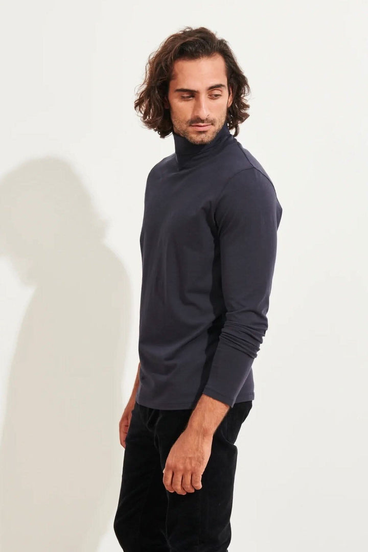Homme portant un col roulé stretch en coton pima, couleur bleu marine, avec une coupe ajustée.
