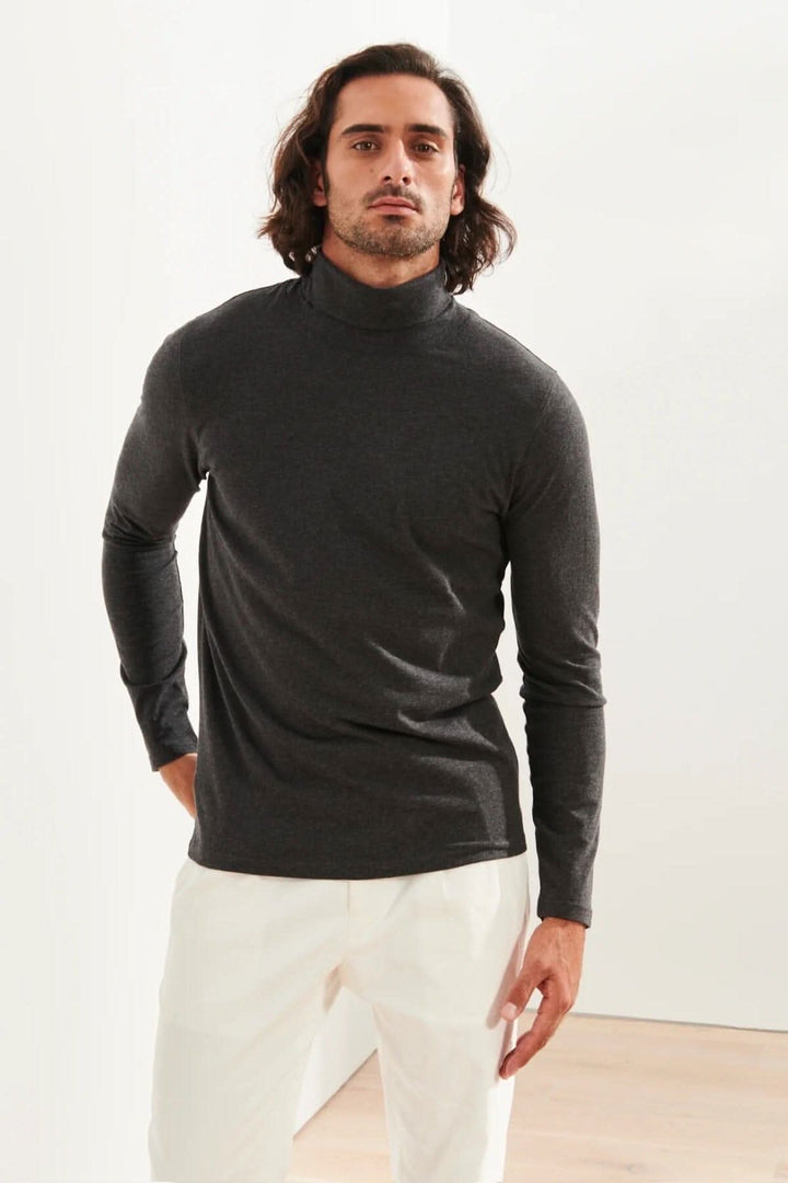 Homme portant un col roulé en coton pima stretch, couleur gris, avec un look élégant et décontracté.