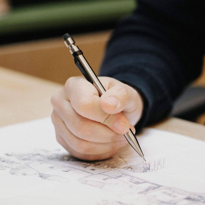 Main image of a hand holding a Crayon Modern Fuel while sketching on paper.