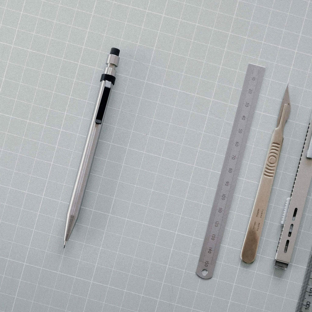 Image de fournitures de bureau incluant un crayon en métal, une règle, un scalpel et d&