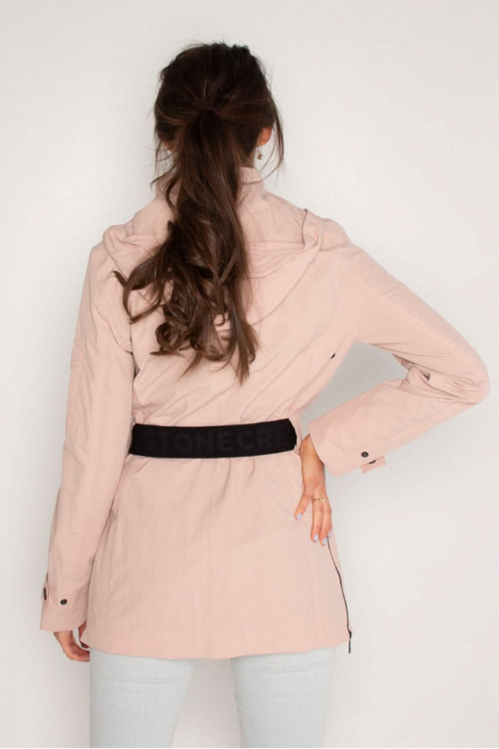 Femme de dos portant une veste légère rose avec ceinture noire, idéale pour le printemps.
