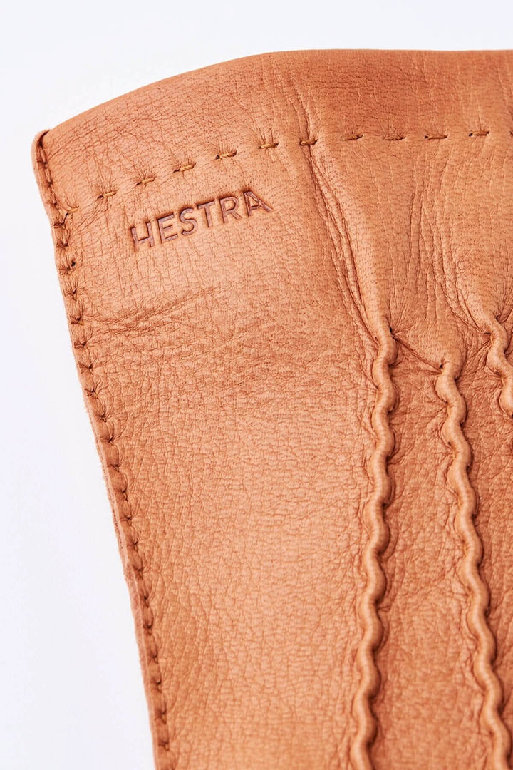 Détail du gant de conduite en cuir avec logo Hestra et coutures raffinées, idéal pour l'automne.