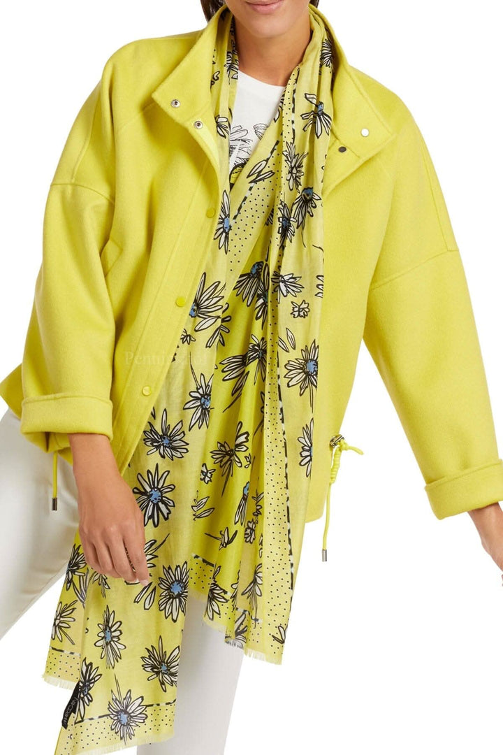 Foulard imprimé marguerites bleues sur fond jaune citron, porté avec une veste jaune.
