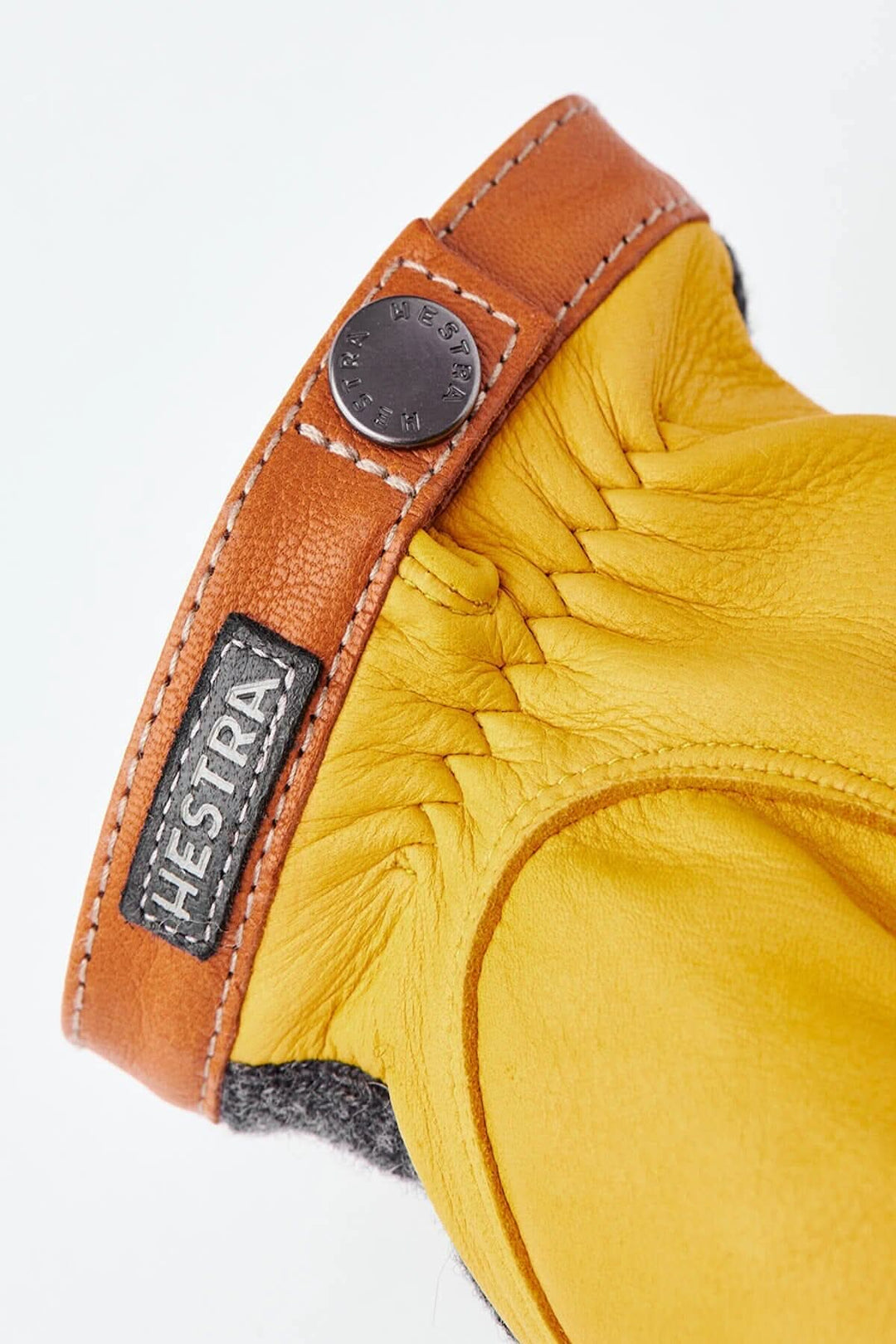 Gant en cuir jaune avec une manchette en cuir marron et logo Hestra, design élégant et chaleureux.