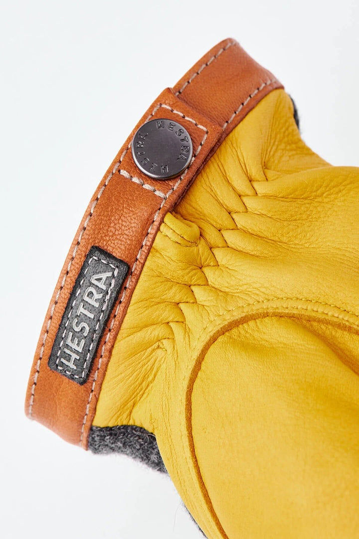 Gant en cuir jaune avec une manchette en cuir marron et logo Hestra, design élégant et chaleureux.