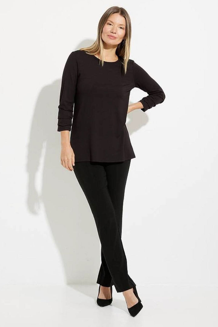 Haut élégant à manches plissées, porté avec un pantalon noir, parfait pour une tenue polyvalente.