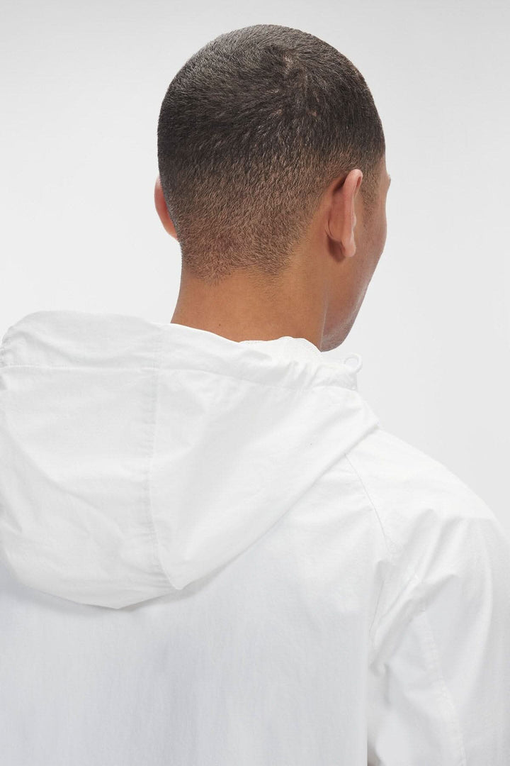 Homme vu de dos portant un hoodie Dyshell blanc avec capuche, mettant en valeur la texture et le design.