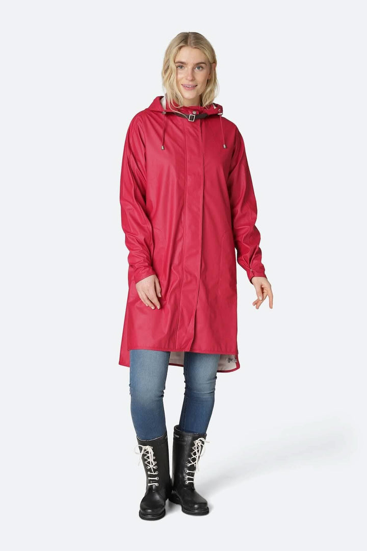 Femme portant un imperméable rouge avec capuche détachable et poches latérales, style pratique et élégant.