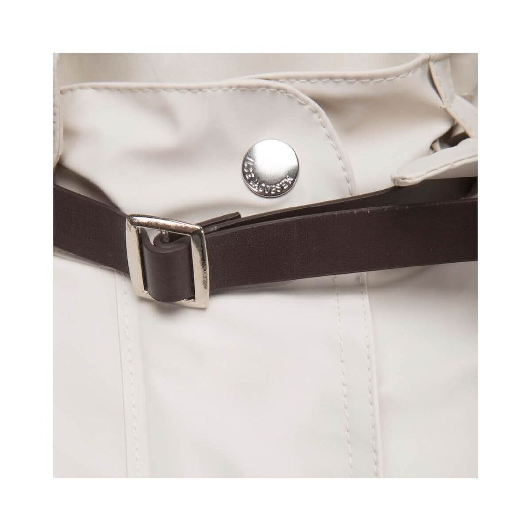 Détail de la sangle en cuir artificiel et bouton d'un imperméable féminin léger.