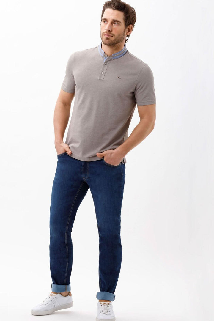Homme portant un polo gris avec un col et un jean bleu slim fit, look moderne et décontracté.