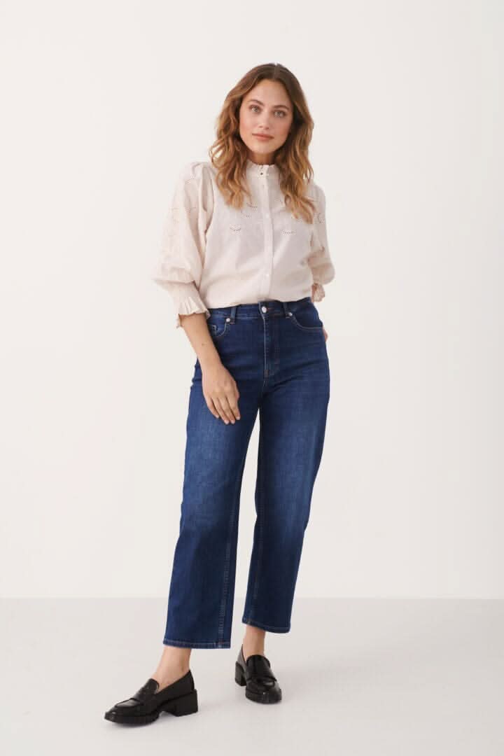 Femme portant le jean Judy à jambe droite et taille haute, terminé avec un chemisier clair et des mocassins.