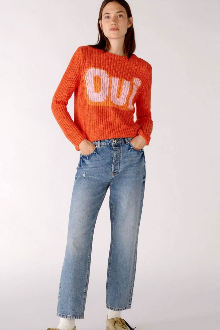 Femme portant un pull orange avec &
