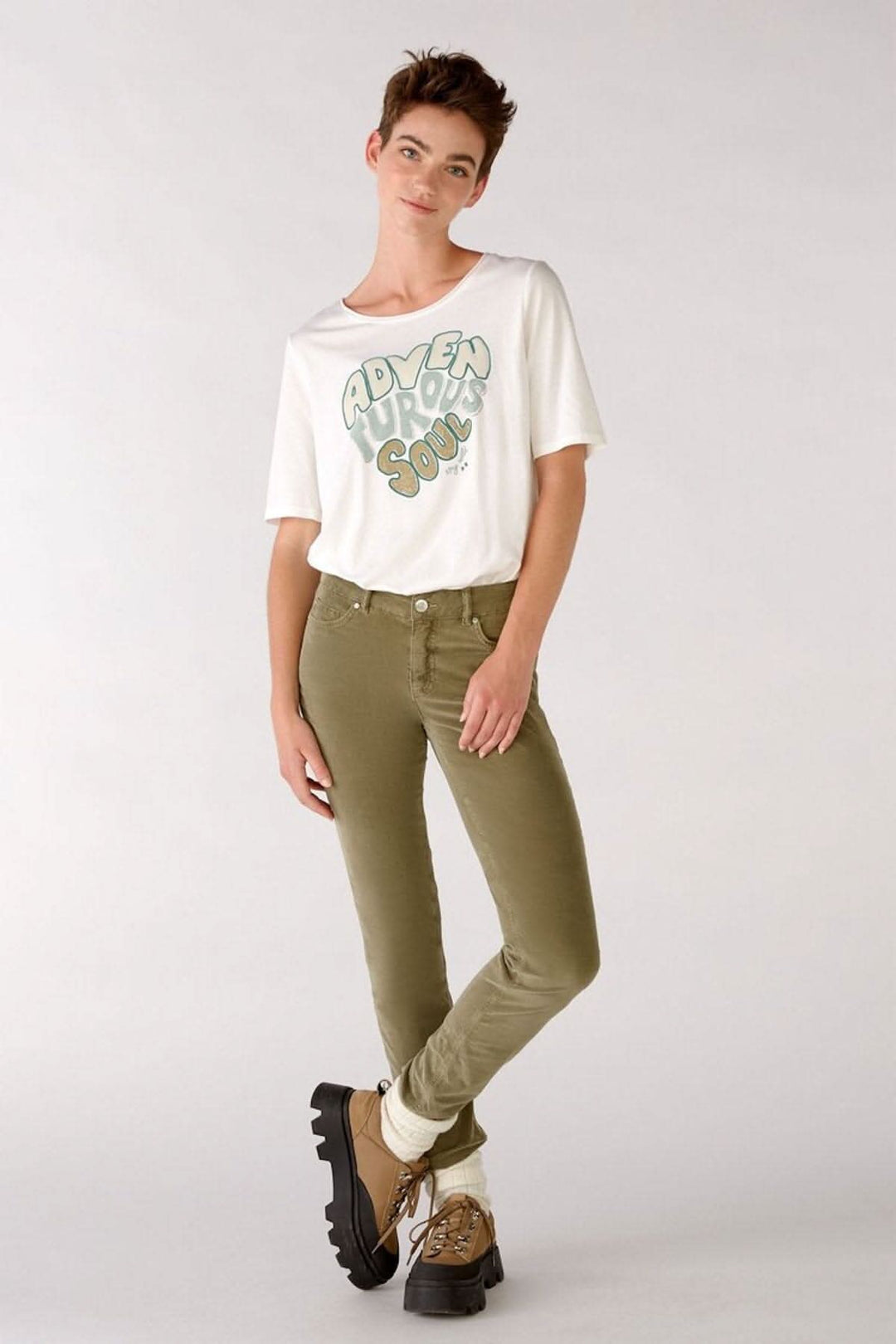Femme portant des jeans en velours verts avec un t-shirt blanc, style décontracté, prêt pour l&