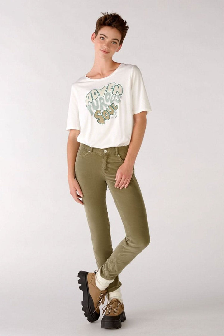 Femme portant des jeans en velours verts avec un t-shirt blanc, style décontracté, prêt pour l&