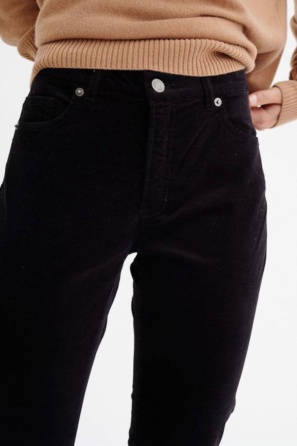 Pantalon en jean noir Tille, coupe régulière, porté avec un pull beige en laine.