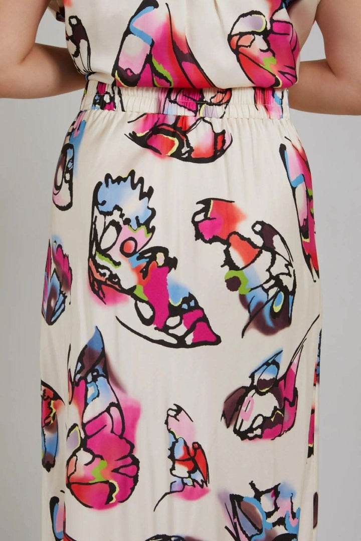 Jupe avec imprimé papillon coloré sur fond ivoire, accentuant une silhouette élégante et confortable.