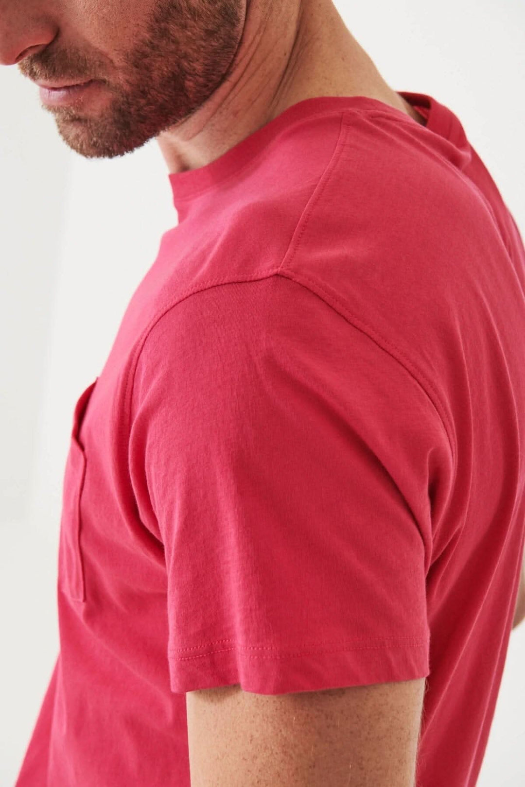 Homme portant un t-shirt léger en coton pima, col rond et poche plaquée, dans une couleur rose.