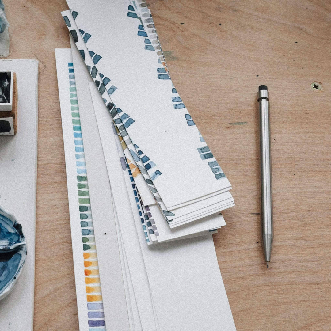 Échantillons de couleurs aquarelle sur papier avec un crayon Modern Fuel en métal sur une table en bois.