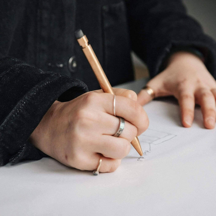 Une main utilisant un crayon Modern Fuel pour dessiner sur du papier, mettant en valeur son design unique.