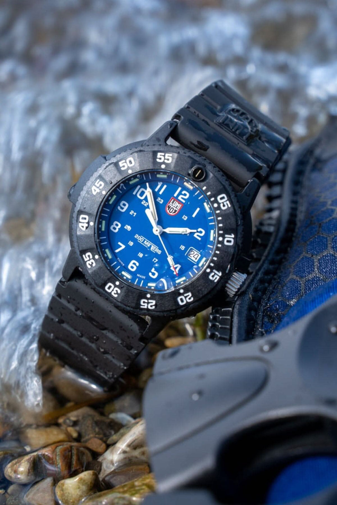 Montre Luminox Navy SEAL 3003.EVO, étanche, cadran bleu, bracelet noir, sur fond de rochers et eau.