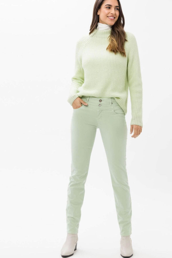 Femme portant un pantalon skinny vert avec un chandail à col montant, style sportif et contemporain.