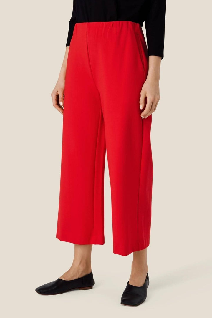 Pantalon en jersey rouge Piri, avec taille élastique et longueur raccourcie, porté par une femme.