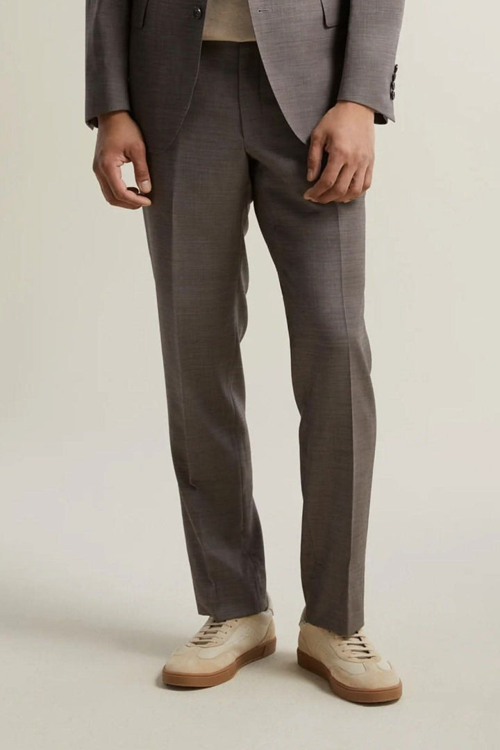 Pantalon habillé pour homme en laine, coupe contemporaine, coloris gris, porté avec des chaussures blanches.